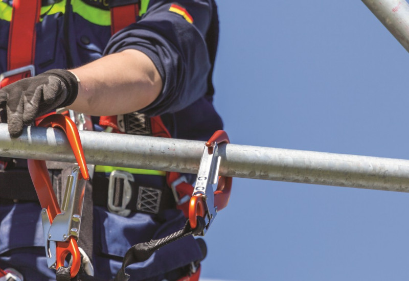 Das Bild zeigt eine Einsatzperson mit einem Klettergurt, der sich in einem Metallgestell eingehängt hat.