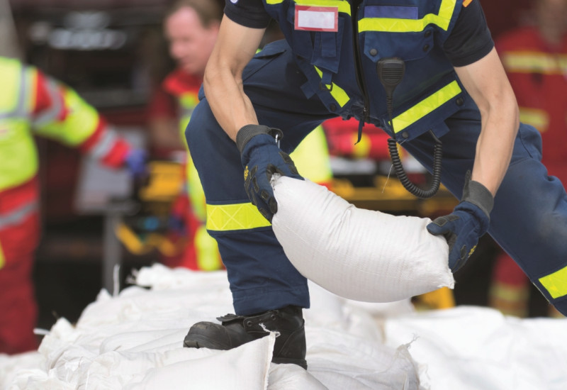 The picture shows emergency workers stacking sandbags.