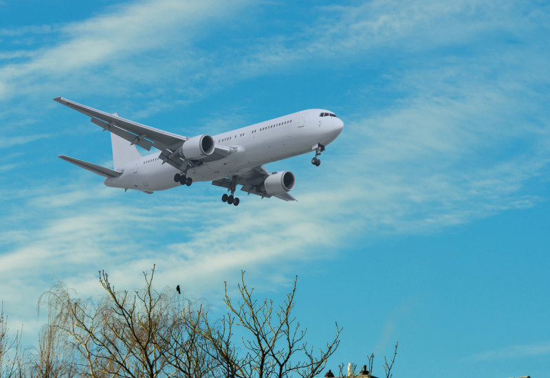 Ein Flugzeug, welches direkt über ein Hausdach fliegt und somit viel Lärm erzeugt 