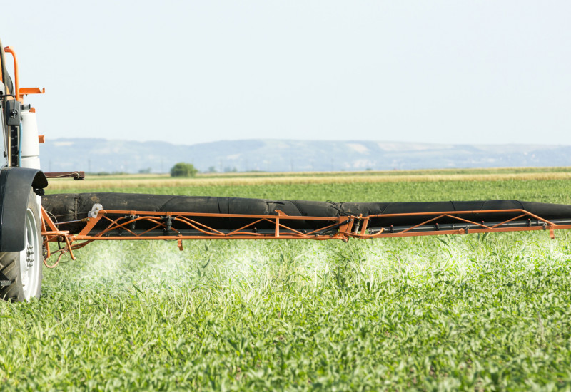 A field with a crop protection device that spreads fertilizer