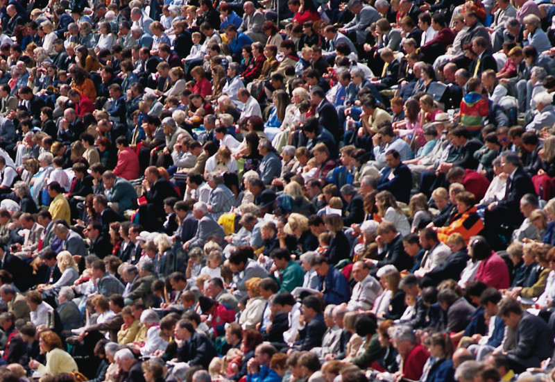 Viele Menschen sitzen nebeneinander und schauen in die selbe Richtung