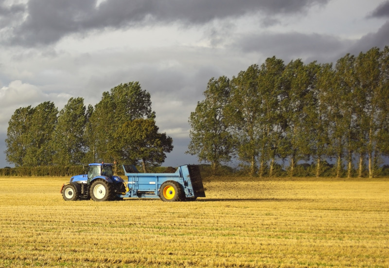 A tractor spreading fertilizer on a field 