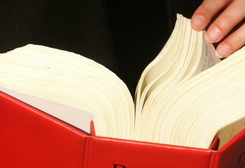 Ein dickes rotes Gesetzbuch, dass umgeblättert wird.