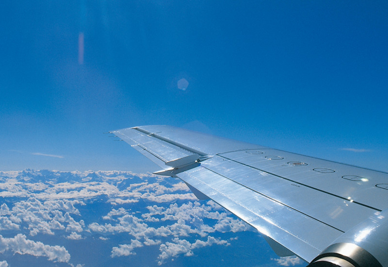 rechter Flugzeugflügel über den Wolken bei blauem Himmel