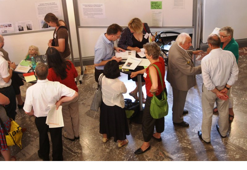 Personen stehen in Gruppen zusammen und tauschen sich aus.