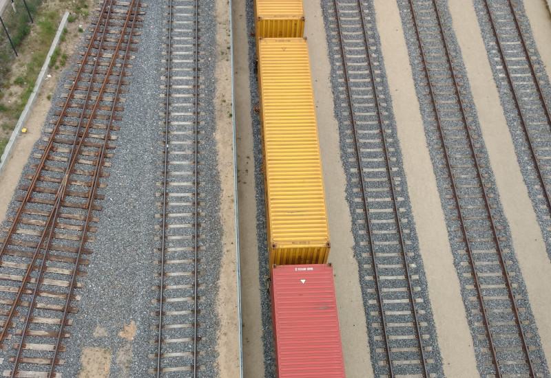 Schieneninfrastruktur im Osnabrücker Hafen. Ein Zug mit gelb und roten Waggons ist von oben sichtbar.