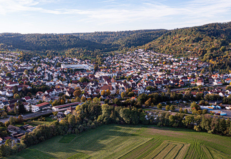 Blick auf Rudersberg, Quelle: Quelle: Gemeinde Rudersberg. Blick aus der Vogelsperspektive über die Gemeinde Rudersberg. Vorne befindet sich ein großes Feld und im Hintergrund Hügel.