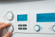 Eine Hand dreht an einem Einstellknopf einer weißen Heizungsanlage, die ein digitales Display mit der Temperaturanzeige 38 Grad Celsius hat.