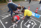 Eltern und Kinder malen das Straßenschild "verkehrsberuhigter Bereich" auf den Asphalt