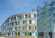 Gebäude des UBA in Dessau Roßlau: verglaster Eingangsbereich und Holzfassade mit bunten Glasscheiben in Grüntönen