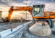 Bagger auf der Baustelle räumt Abfall in Container