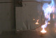 Ein Metallrohr ist U-förmig vor einer Wand gebogen. Auf der rechten Seite lodert eine große Flamme das ganze Rohr entlang.