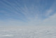 Eine Eisschicht so weit das Auge reicht. Der Himmel ist bilderbuchblau und nur eine dünne Wolkenschicht ist am Horizont zu sehen. 
