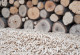 Holzpellets vor einem Holzstapel
