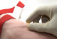 An einem Arm wird Blut abgenommen, ein weißer Handschuh sticht mit der Nadel gerade in die Vene.
