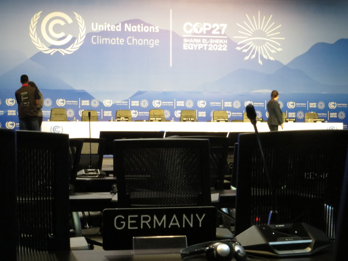 Saal mit Sitzreihen auf der COP27, auf einem Platz steht ein Schild "Germany", ein Mikrofon und ein Kopfhörer