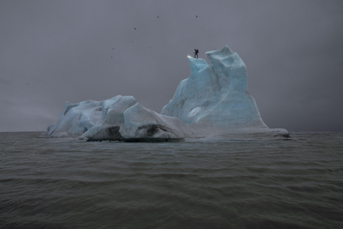 Eisberg im Meer auf dem eine Schattenfigut steht