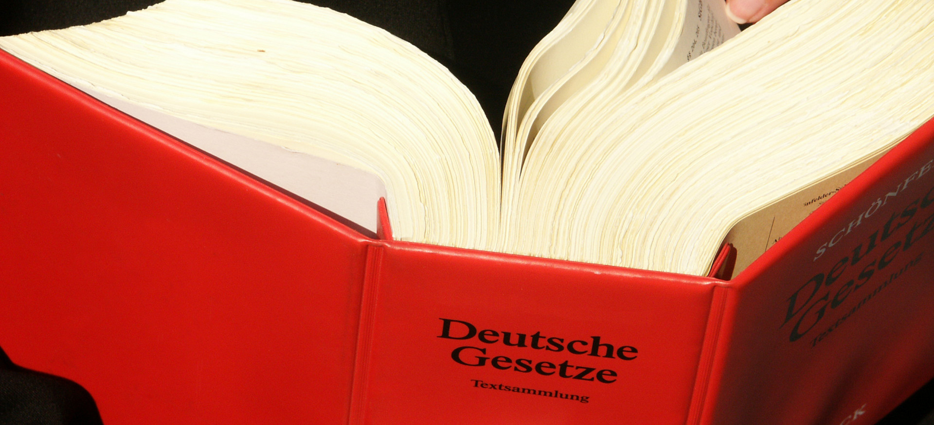 Ein dickes rotes Gesetzbuch, dass umgeblättert wird.