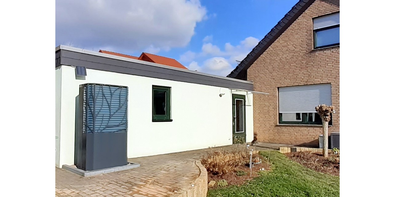 Auf der linken Seite der Garagenrückseite steht die Wärmepumpe. Rechts schließt sich die Giebelwand des Hauses an.
