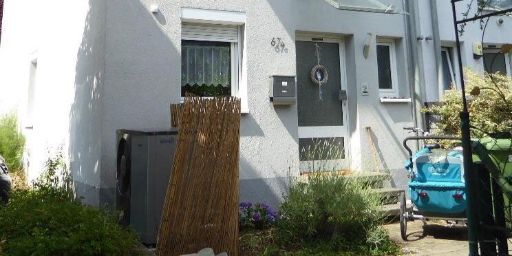 Eine Wärmepumpe steht vor einem weißen Haus