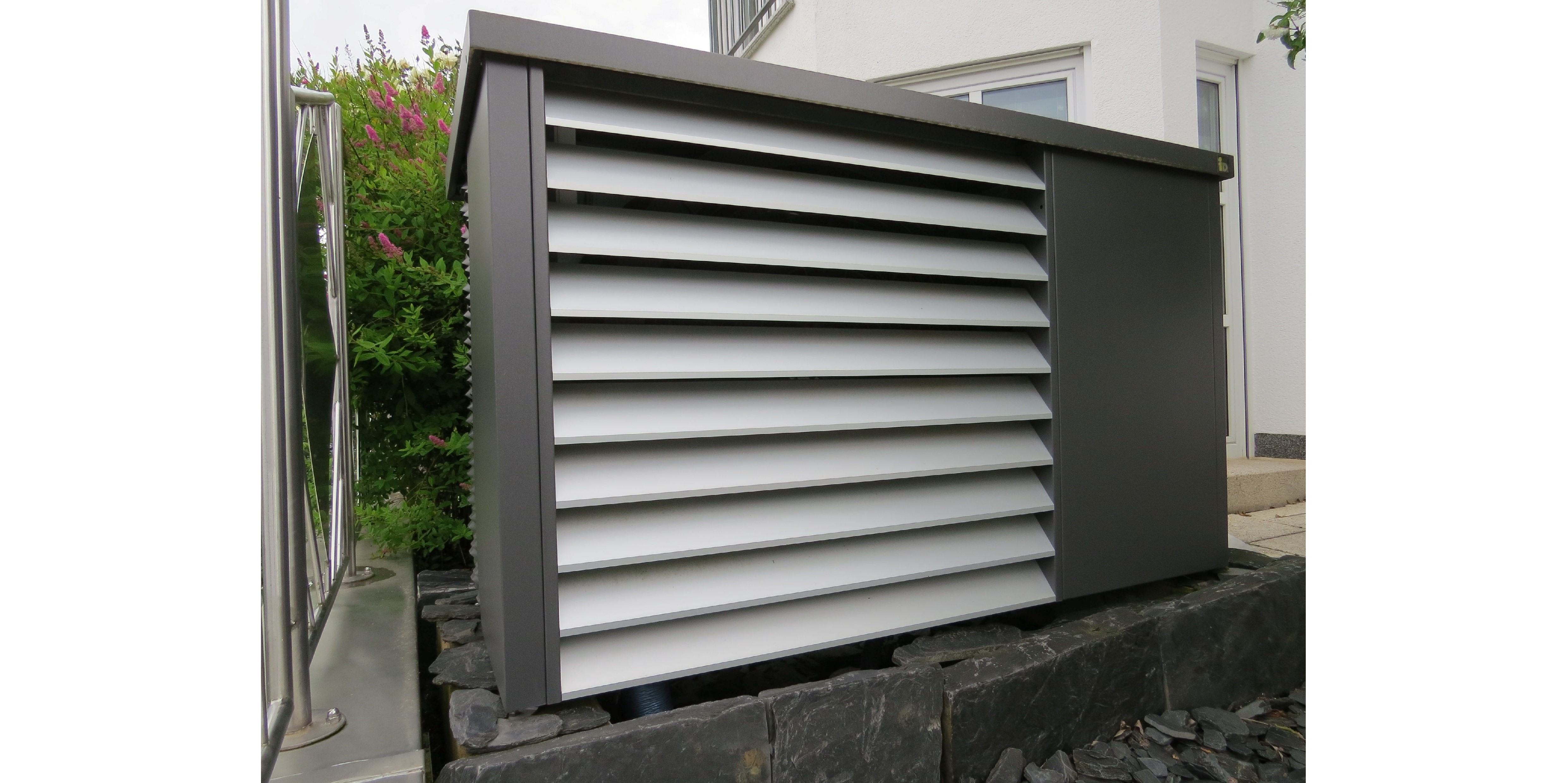 Eine Großaufnahme der dunkelgrauen Außeneinheit der Wärmepumpe mit hellgrau wirkenden Lamellen