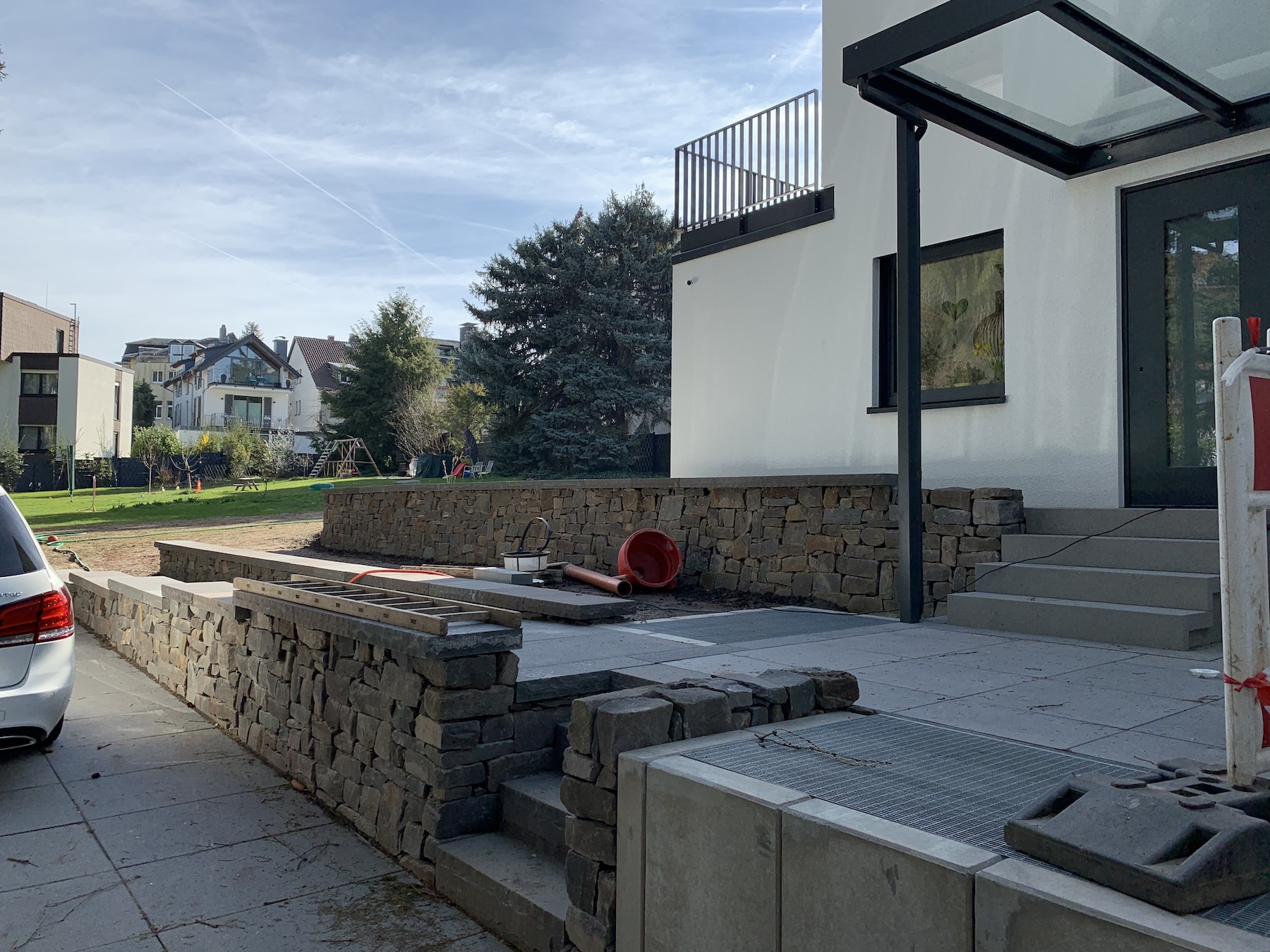 In Boden eingelassene Gitter des Lüftungsschachts der Wärmepumpe, am Rand des Aufgangs zum Hauseingang.