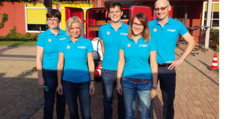 Mehrere Personen, die das gleiche hellblaue T-Shirt tragen, posieren für ein Gruppenfoto.