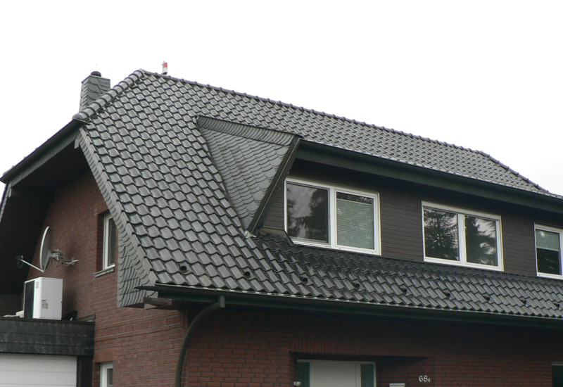 Ein Einfamilienhaus mit angebauter Garage mit Wärmepumpe auf dem Dach.