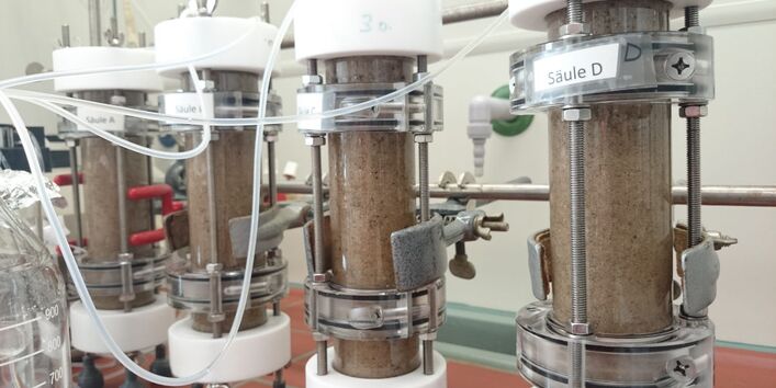 Vier Glas-Laborsäulen, befüllt mit sandigem Boden 