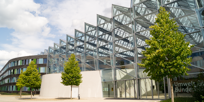 modernes Bürogebäude mit viel Glas, davor Bäume, am Eingang Schriftzug Umweltbundesamt