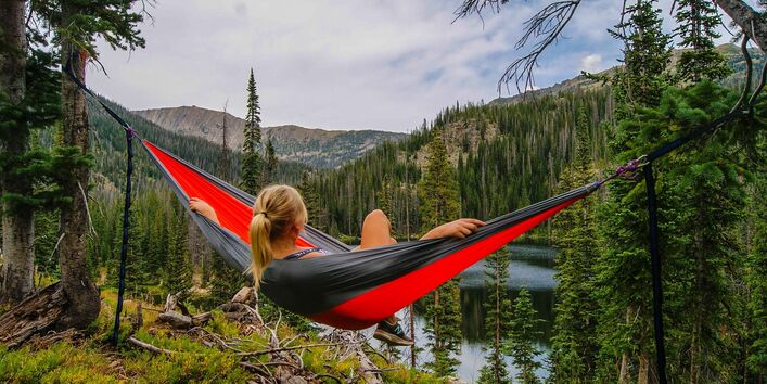 Frau in der Natur liegt in einer Hängematte.