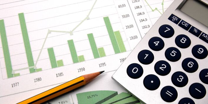 Das Bild zeigt einen Taschenrechner neben einem Balken- und einem Kuchendiagramm und steht symbolisch für die Berechnung der Finanzmittel