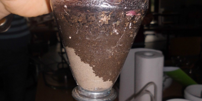 Wasser befeuchtet sandigen Boden im Trichter – wird alles gleich unten herausströmen oder nicht?