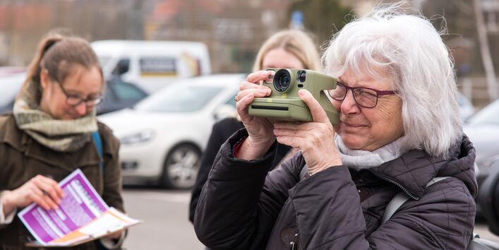 Ältere Dame mach mit einer Polaroid-Kamera ein Foto
