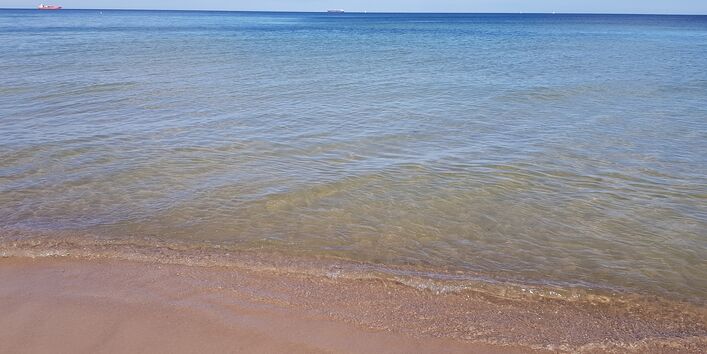 Leerer Sandstrand, kleine Wellen.
