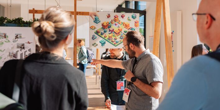 Teilnehmende betrachten graphische Arbeiten in der Ausstellung „Stadtansichten“.