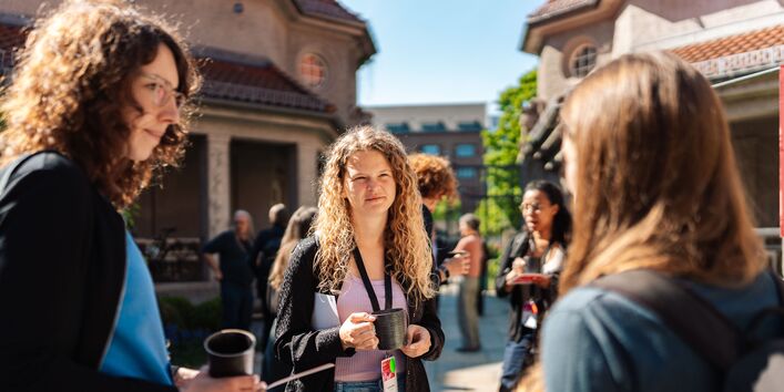 Mehrere Personen unterhalten sich im Außenbereich des Veranstaltungsorts.