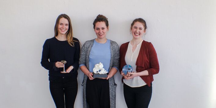 drei junge Frauen mit Trophäen lehnen an einer Wand