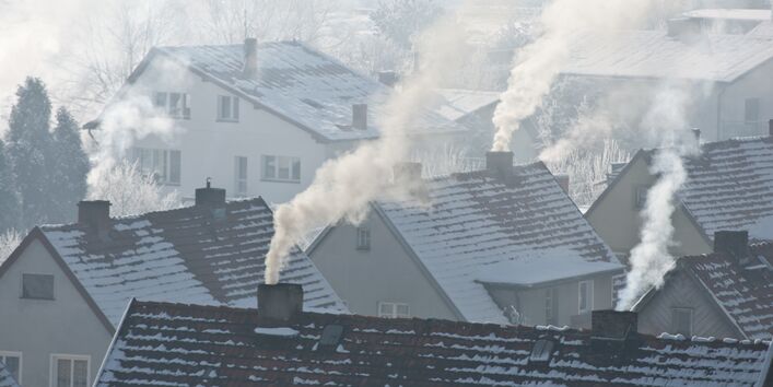 Über verschneiten Dächern qualmen etliche Schornsteine 