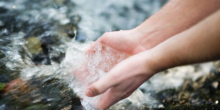 Zwei Hände in einem klaren Bach