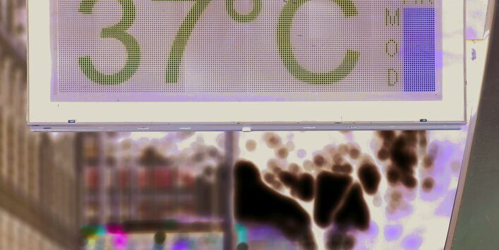 Das Bild zeigt eine digitale Temperaturanzeige in einer Stadt. Der angezeigte Wert beträgt 37 °C.