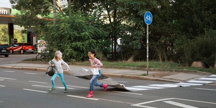 Kinder laufen mit einem Zebrastreifen über die Straße