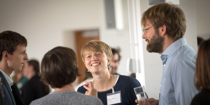 Teilnehmerinnen und Teilnehmer stehen unterhaltend und lachend beisammen.