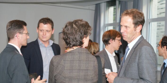 Teilnehmergruppe steht im Veranstaltungsraum und diskutiert miteinander.