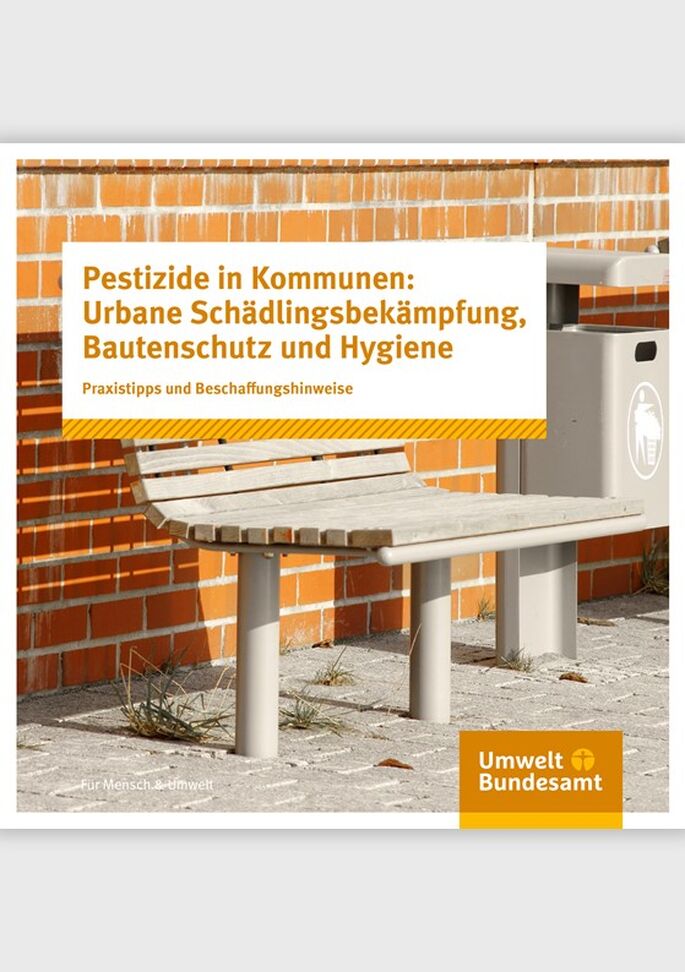 Eine Sitzbank und ein Mülleimer vor einer Backsteinmauer