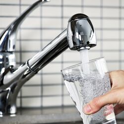 aus einem Wasserhahn läuft Trinkwasser in ein Glas