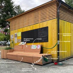 Das Bild zeigt die Regenwasserbank an der MachBar in Stuttgart. Ein durch nachbarschaftsinnitiative getragenes Projekt, welches das gesammelte Regenwasser zur Bewässerung des Grüns auf dem Platz nutzt. 
