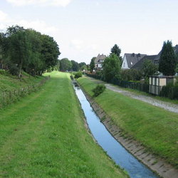 Foto: Der begradigte und mit Betonschalen ausgebaute Heerener Mühlbach in Kamener Wohnumfeld.