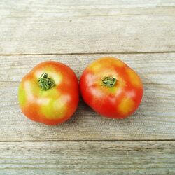 2 Tomaten mit Grünkragen auf hölzernem Untergrund