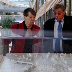 Barbara Hendricks und UBA-Vizepräsident Holzmann stehen an einer Vitrine und betrachten ein Modell des UBA-Gebäudes in Dessau-Roßlau.